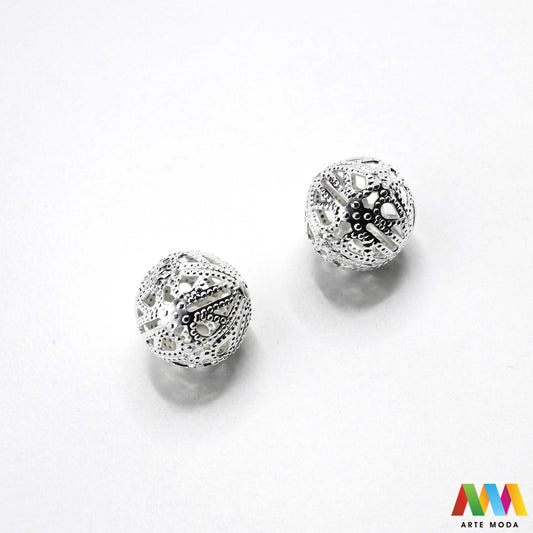 Elegantne metalne filigranske perle u srebrnoj, zlatnoj i nikal boji izložene na površini za izradu nakita. Prikazane su šupljikave i čipkaste metalne kuglice te ovalni filigranski distanceri s raznolikim vintage i orijentalnim uzorcima. Kvalitetan metalni repromaterijal i lagani razdjelnici s izbušenim rupama za provlačenje konca i igala, namijenjeni za izradu unikatnih narukvica, visećih naušnica i bogatih ogrlica u kreativnim DIY radionicama za izradu ručno rađenog modnog nakita arte moda repromaterijali
